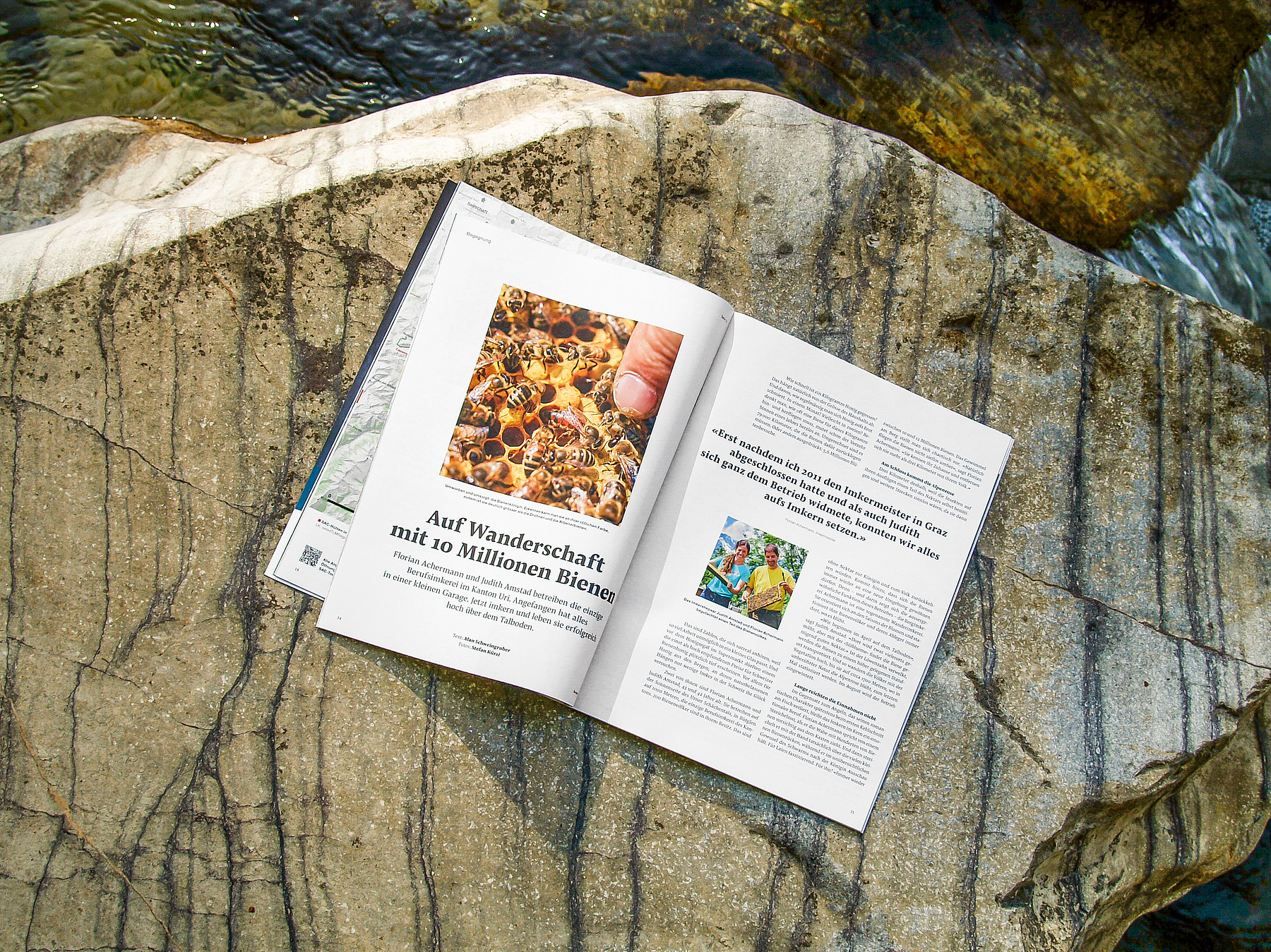 Auf einem Felsbrocken im Grünen liegt eine aufgeschlagene Ausgabe der SAC-Zeitschrift «Die Alpen» und zeigt Bergfotografien.