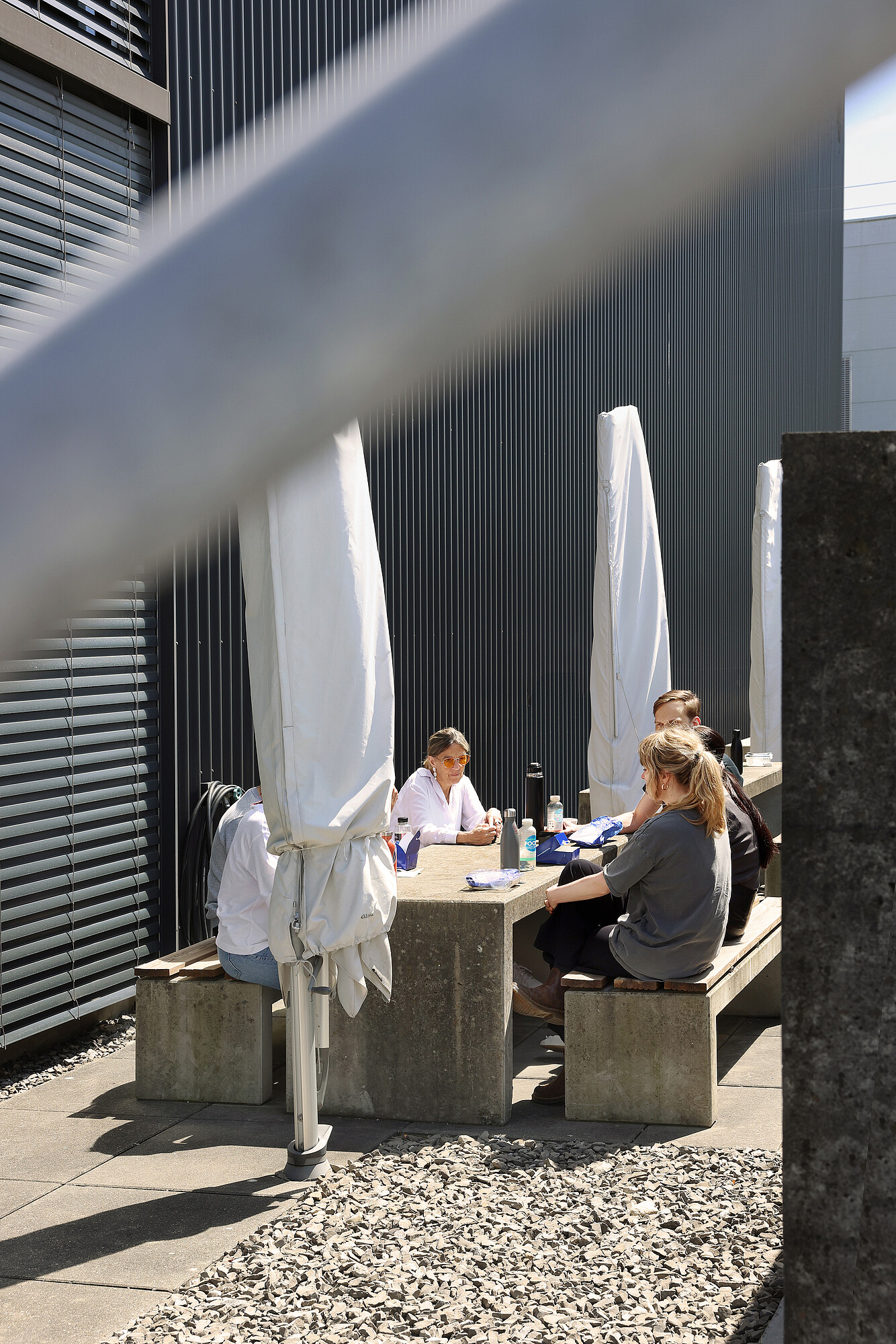 Einige Mitarbeitende sitzen gemeinsam an einem Tisch an der Sonne.